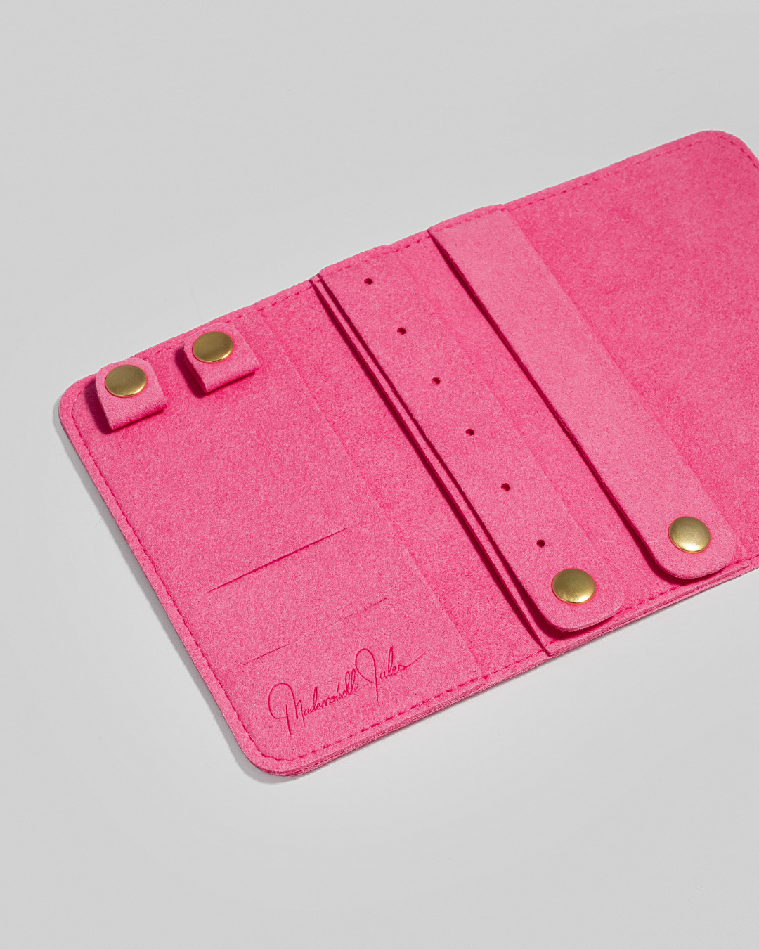 Pink jewelry pouch with gold accents on a light gray background